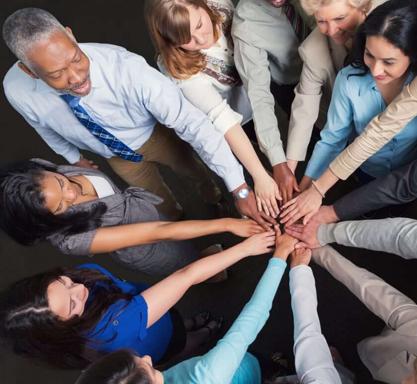 A diverse team joining hands in the center of a circle